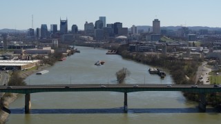 DX0002_112_028 - 5.7K aerial stock footage passing a bridge with view of barge sailing toward the city's skyline, Downtown Nashville, Tennessee