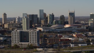 DX0002_114_037 - 5.7K aerial stock footage descend by apartment complex, focus on city's tall skyline by the convention center in Downtown Nashville, Tennessee