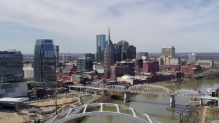 DX0002_116_002 - 5.7K aerial stock footage fly away from and past skyscrapers, and bridge spanning the river in Downtown Nashville, Tennessee