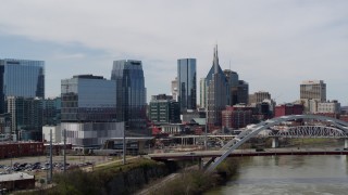 5.7K aerial stock footage of office high-rise and skyscrapers seen from river and bridge in Downtown Nashville, Tennessee Aerial Stock Footage | DX0002_116_022