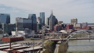 5.7K aerial stock footage of descending by the river and bridge, focus on skyscrapers in Downtown Nashville, Tennessee Aerial Stock Footage | DX0002_116_026