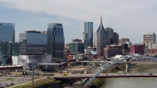 DX0002_116_027 - 5.7K aerial stock footage flyby the river and bridge, approach office building and skyscrapers in Downtown Nashville, Tennessee