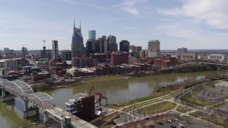 5.7K aerial stock footage reverse view of the city's riverfront skyscrapers, descend near pedestrian bridge, Downtown Nashville, Tennessee Aerial Stock Footage | DX0002_117_004