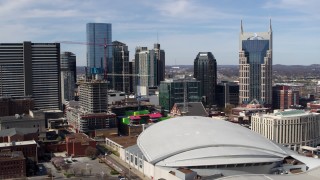 DX0002_117_043 - 5.7K aerial stock footage of flying by Bridgestone Arena with a view of the skyline, Downtown Nashville, Tennessee