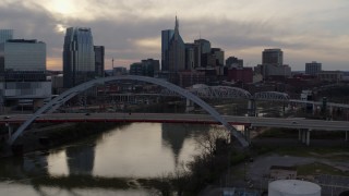 5.7K aerial stock footage passing the bridge on Cumberland River at sunset, skyline behind it, Downtown Nashville, Tennessee Aerial Stock Footage | DX0002_119_046