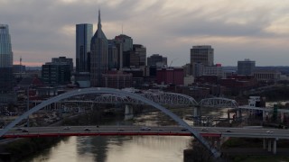 DX0002_120_011 - 5.7K aerial stock footage flying by the riverfront skyscrapers and bridges spanning the Cumberland River at sunset, Downtown Nashville, Tennessee