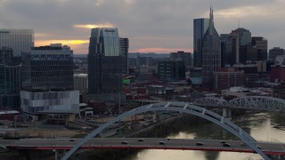 5.7K aerial stock footage focus on a tall skyscraper while flying by a bridge on the river at sunset, Downtown Nashville, Tennessee Aerial Stock Footage | DX0002_120_015