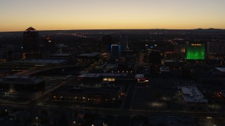 DX0002_123_030 - 5.7K aerial stock footage of passing DoubleTree hotel with blue lighting near office buildings at twilight, Downtown Albuquerque, New Mexico