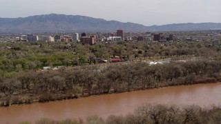 DX0002_124_002 - 5.7K aerial stock footage of high-rise office buildings seen while ascending by the Rio Grande, Downtown Albuquerque, New Mexico