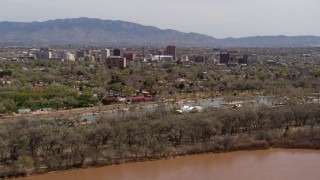 DX0002_124_016 - 5.7K aerial stock footage of high-rise office buildings seen while flying by park and Rio Grande, Downtown Albuquerque, New Mexico