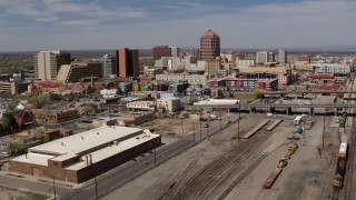 5.7K aerial stock footage reverse view of distant office buildings seen from train tracks, Downtown Albuquerque, New Mexico Aerial Stock Footage | DX0002_124_039