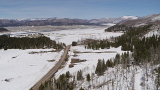 5.7K aerial stock footage of a country road in snowy valley with view of mountains, New Mexico Aerial Stock Footage | DX0002_134_019