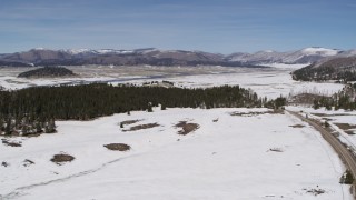 5.7K aerial stock footage flyby evergreens in valley with view of distant mountains to reveal country road, New Mexico Aerial Stock Footage | DX0002_134_022