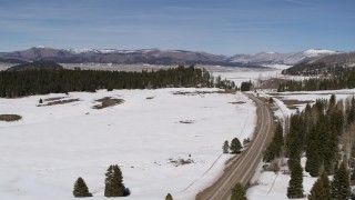 5.7K aerial stock footage pass a lonely country road in snowy valley with view of distant mountains, New Mexico Aerial Stock Footage | DX0002_134_024