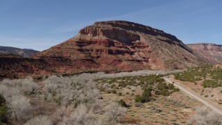 DX0002_135_001 - 5.7K aerial stock footage of black cars on a desert road near a butte, New Mexico