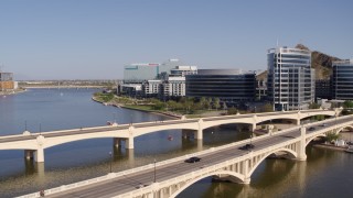 DX0002_142_007 - 5.7K aerial stock footage black car and truck on bridge near office buildings in Tempe, Arizona