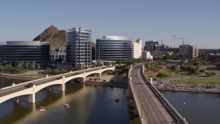 DX0002_142_009 - 5.7K aerial stock footage orbiting waterfront office buildings beside bridges spanning Tempe Town Lake in Tempe, Arizona