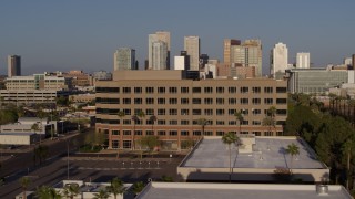 5.7K aerial stock footage flying by state offices to reveal Adams Street leading to the city's skyline at sunset in Downtown Phoenix, Arizona Aerial Stock Footage | DX0002_143_006