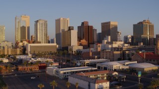 DX0002_143_027 - 5.7K aerial stock footage of an approach to tall buildings in the city's skyline of Downtown Phoenix, Arizona, sunset