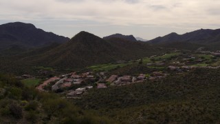 5.7K aerial stock footage reverse view of homes and golf course, reveal small peak with cactus plants in Tucson, Arizona Aerial Stock Footage | DX0002_145_007