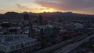 5.7K aerial stock footage ascend by railroad tracks toward high-rise office towers and setting sun in Downtown Tucson, Arizona Aerial Stock Footage | DX0002_146_038