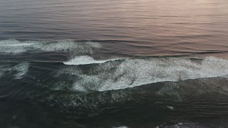 DX0002_148_025 - 4K aerial stock footage of flying away from ocean waves to reveal the beach at sunset, Long Beach, Washington