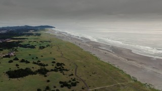 DX0002_148_028 - 4K aerial stock footage approach the beach and ocean waves at sunset in Long Beach, Washington