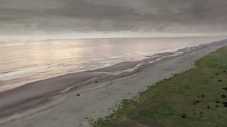 DX0002_148_034 - 4K aerial stock footage approach the beach at sunset, pan across the ocean in Long Beach, Washington