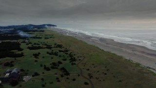 DX0002_148_036 - 4K aerial stock footage fly toward the beach as fireworks go off at sunset in Long Beach, Washington