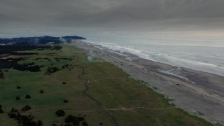 DX0002_148_037 - 4K aerial stock footage of the beach as fireworks go off at sunset in Long Beach, Washington