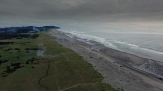 4K aerial stock footage reverse view of the beach as fireworks go off at sunset in Long Beach, Washington Aerial Stock Footage | DX0002_148_038