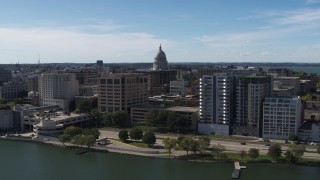 5.7K aerial stock footage descend and fly away from the capitol dome surrounded by office buildings, Madison, Wisconsin Aerial Stock Footage | DX0002_158_029