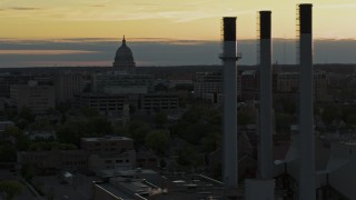 DX0002_161_028 - 5.7K aerial stock footage flyby the capitol dome at sunset, reveal smoke stacks, Madison, Wisconsin