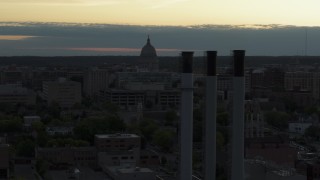 5.7K aerial stock footage focus on the capitol dome at sunset, reveal and fly away from smoke stacks, Madison, Wisconsin Aerial Stock Footage | DX0002_162_003