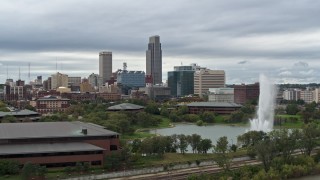 5.7K aerial stock footage fly over river toward a fountain and park with view of skyline, Downtown Omaha, Nebraska Aerial Stock Footage | DX0002_169_023