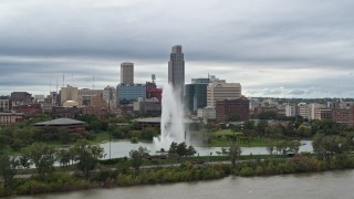 DX0002_169_027 - 5.7K aerial stock footage passing by a fountain in a park and skyline, Downtown Omaha, Nebraska