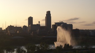 DX0002_172_013 - 5.7K aerial stock footage focus on skyscraper while passing fountain at sunset, Downtown Omaha, Nebraska