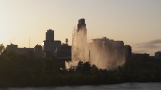 DX0002_172_015 - 5.7K aerial stock footage focus on skyscraper while flying by fountain at sunset, Downtown Omaha, Nebraska