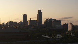 DX0002_172_016 - 5.7K aerial stock footage focus on skyscraper while ascending near fountain at sunset, Downtown Omaha, Nebraska