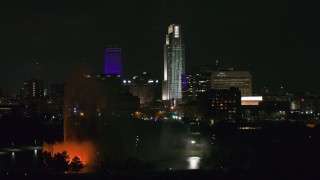 DX0002_173_057 - 5.7K aerial stock footage flying by skyscrapers and high-rises at night, reveal the park fountain, Downtown Omaha, Nebraska