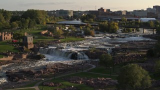 DX0002_176_008 - 5.7K aerial stock footage of orbiting waterfalls at sunset in Sioux Falls, South Dakota