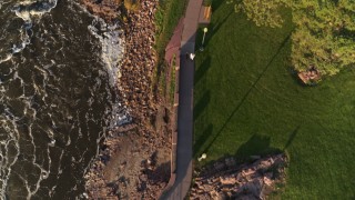 DX0002_176_016 - 5.7K aerial stock footage a bird's eye view of a path through the park by the river at sunset in Sioux Falls, South Dakota