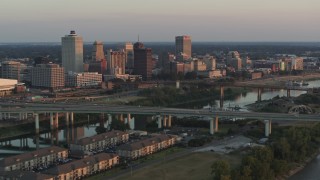 5.7K aerial stock footage of flying by the city's skyline behind the bridge and the river at sunset, Downtown Memphis, Tennessee Aerial Stock Footage | DX0002_181_011