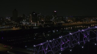 5.7K aerial stock footage of the downtown skyline, reveal the bridge with purple lights at night, Downtown Memphis, Tennessee Aerial Stock Footage | DX0002_187_035