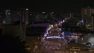 DX0002_188_039 - 5.7K aerial stock footage of flying by arena to reveal numerous Beale Street clubs and restaurants at nighttime, Downtown Memphis, Tennessee