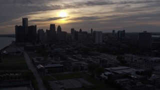 5.7K aerial stock footage of descending past the city's skyline with the setting sun in the clouds above, Downtown Detroit, Michigan Aerial Stock Footage | DX0002_197_007