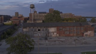 DX0002_197_015 - 5.7K aerial stock footage ascend by abandoned factory building and water tower at sunset, Detroit, Michigan