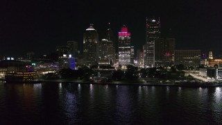 DX0002_199_013 - 5.7K aerial stock footage focus on Hart Plaza and towering skyscrapers at night while descending by river, Downtown Detroit, Michigan