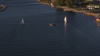 DX0002_203_036 - 5.7K aerial stock footage fly away from a rowboat and speedboat as sailboats arrive at sunset, Buffalo, New York