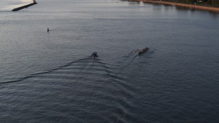 5.7K aerial stock footage of flying away from rowboat and speedboat on Lake Erie at sunset, Buffalo, New York Aerial Stock Footage | DX0002_204_008